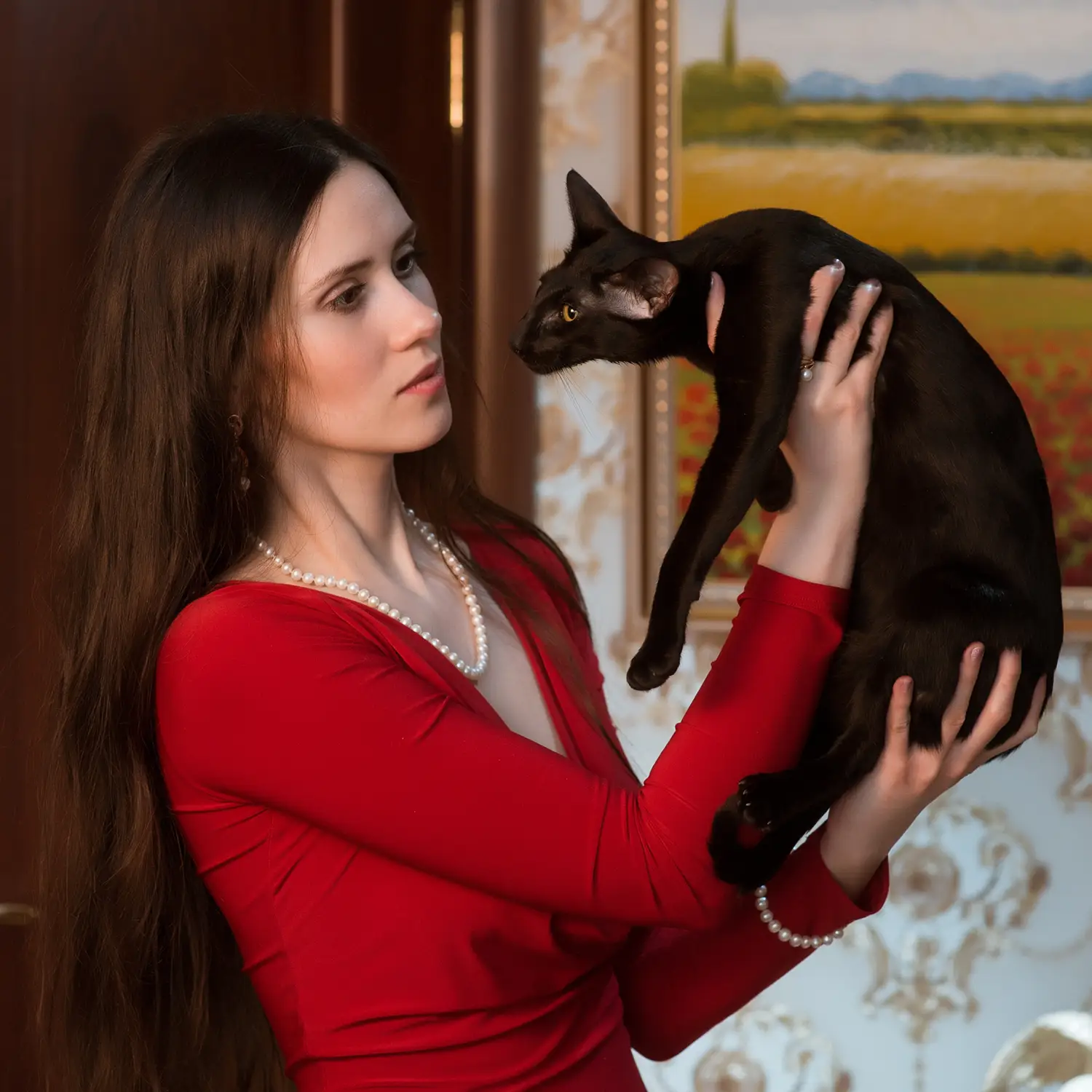 Olga Shatokhina, a breeder of Oriental Shorthair and Siamese cats, holds a black Oriental cat in her arms.